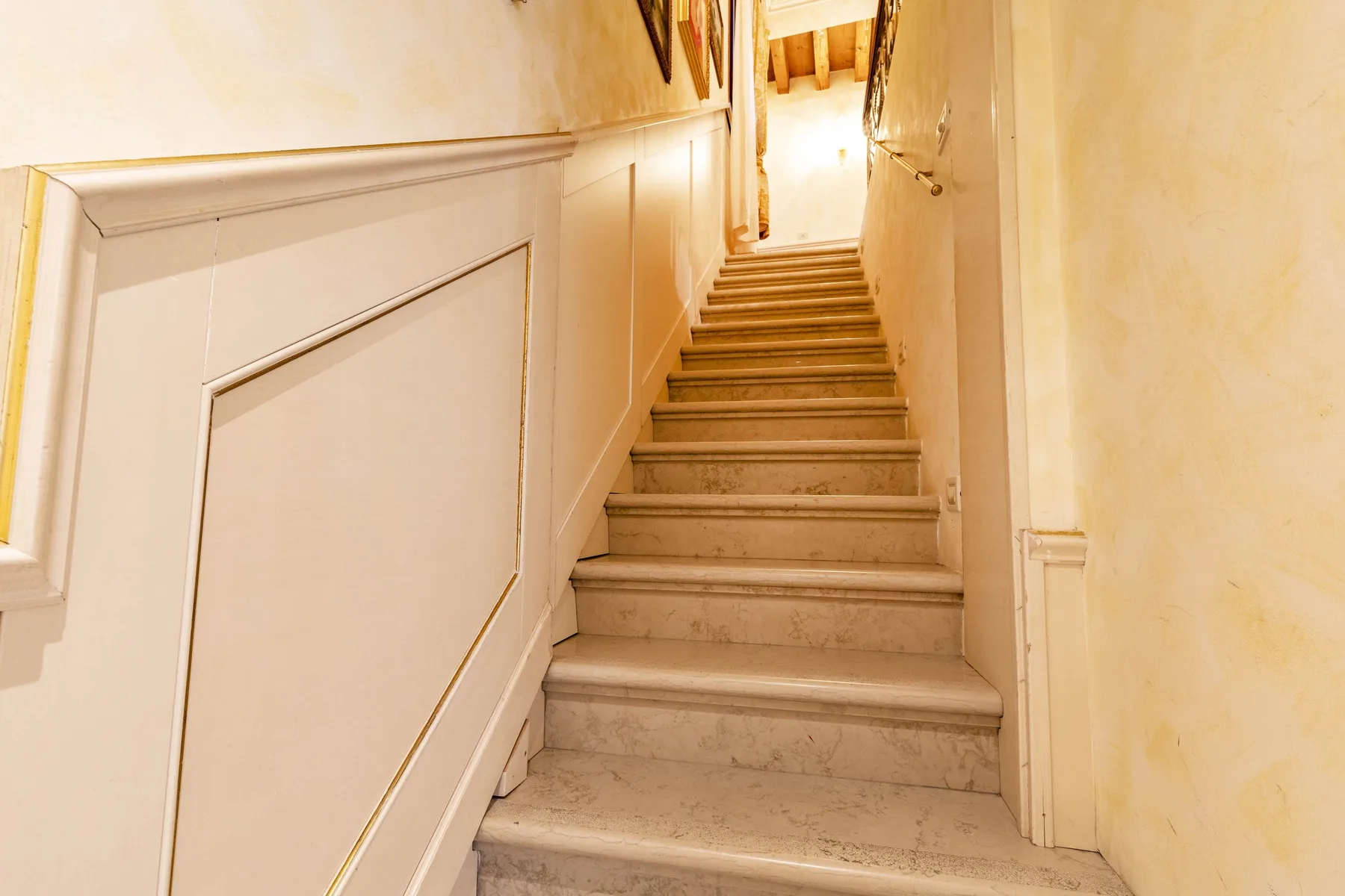 A narrow staircase with light-colored steps leads to a bright upper hallway.