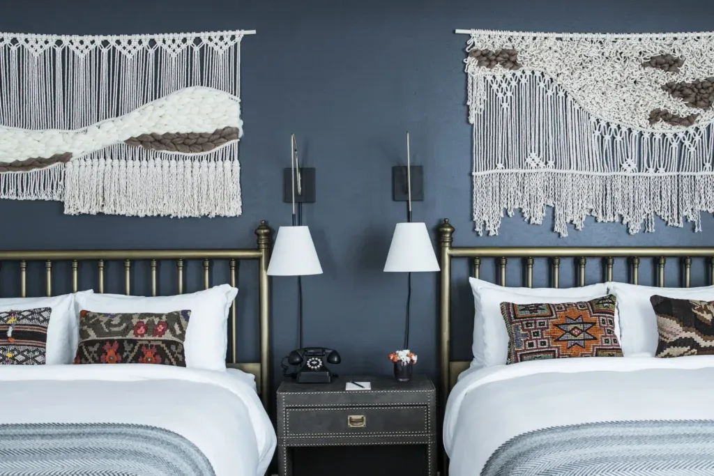 Habitación con dos camas individuales y arte textil en la pared