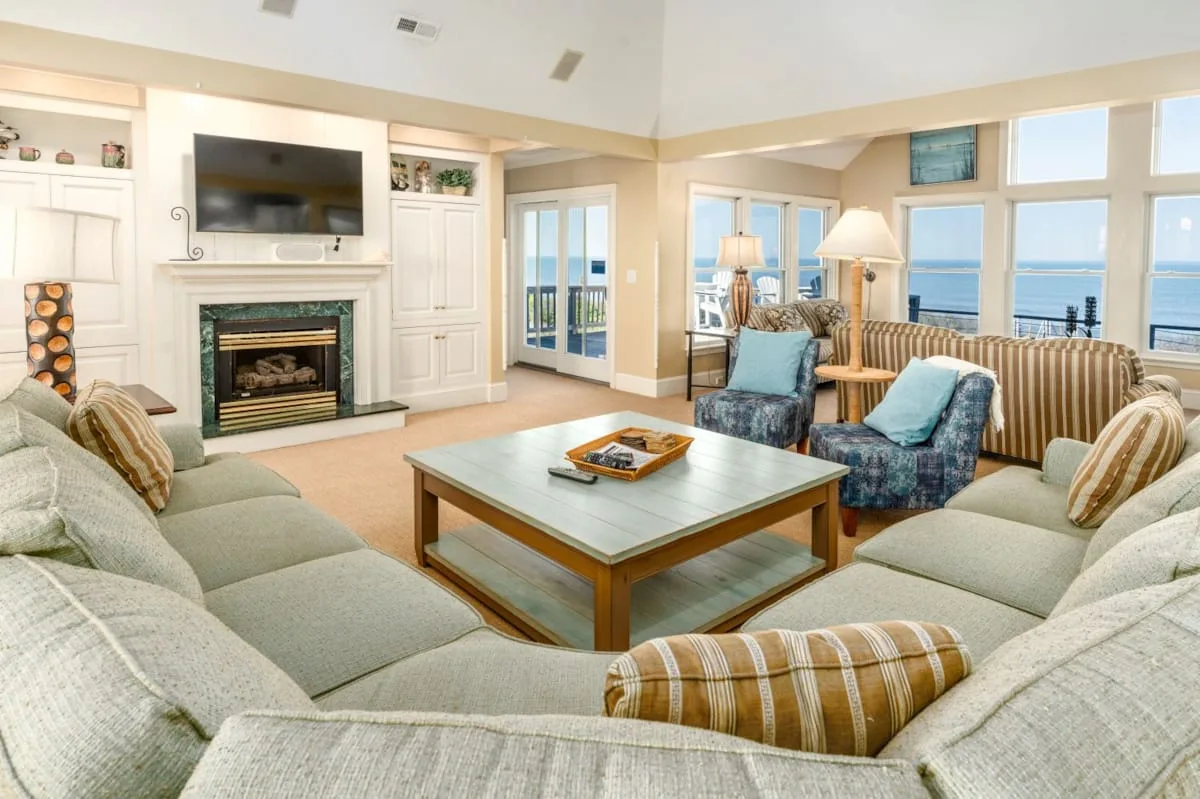 A bright living room with seating arranged around a coffee table and fireplace.