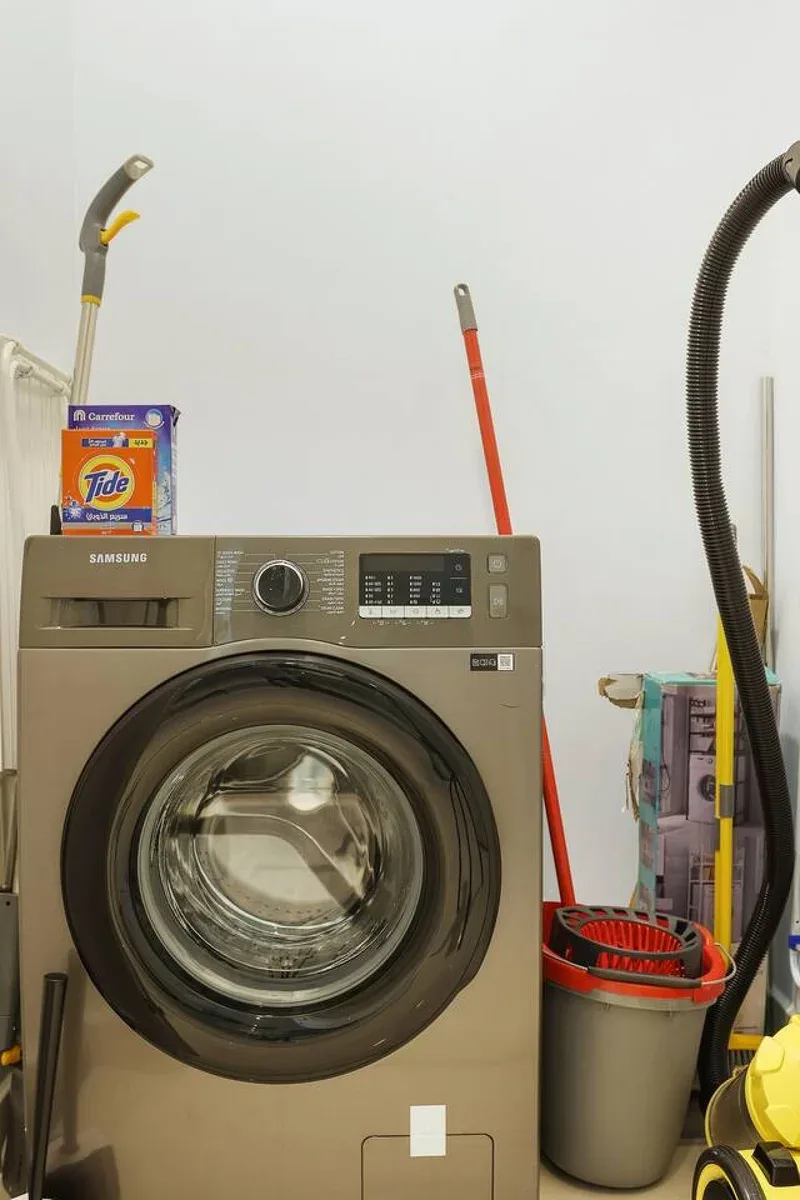 Una zona de lavandería con una lavadora de carga frontal y productos de limpieza.