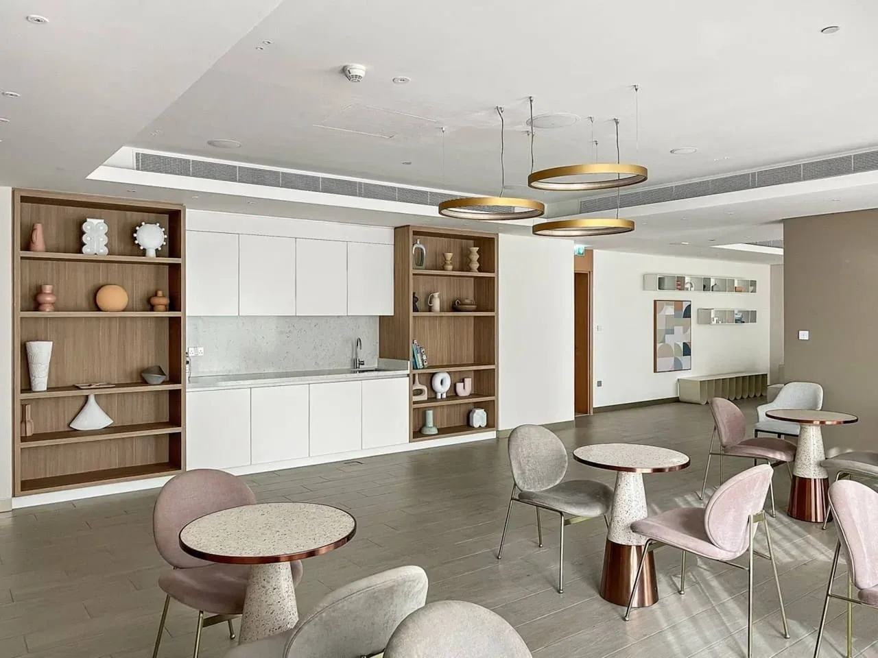 Una sala moderna tiene una pequeña cocina integrada y varias zonas para sentarse.