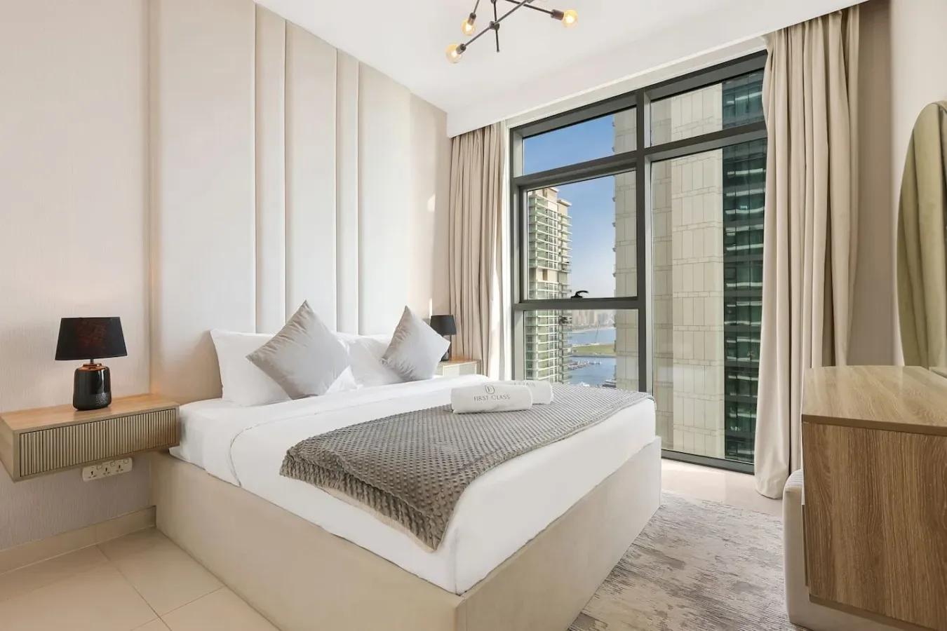 Un dormitorio con una cama bien tendida junto a una ventana grande.