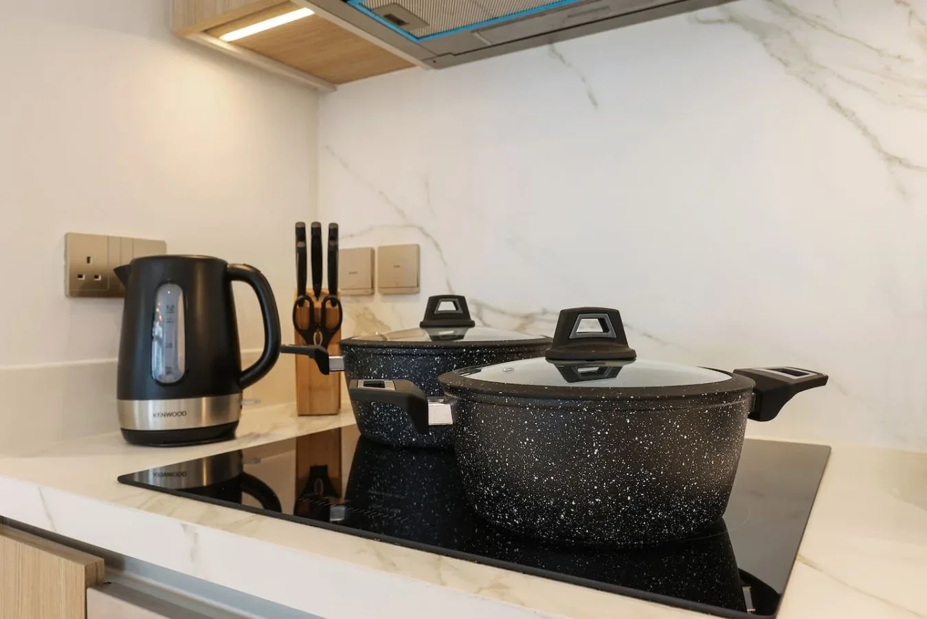 Una cocina con una olla moteada sobre la placa y un hervidor eléctrico en la encimera.