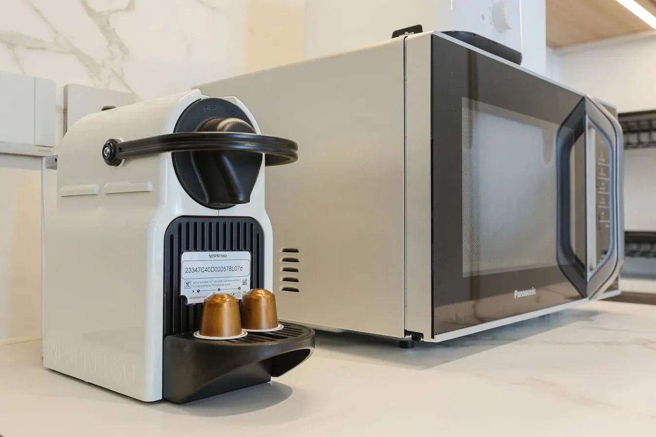 Una cafetera de encimera está junto a un microondas en una cocina luminosa.