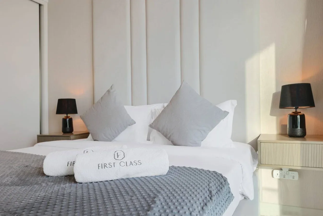 Una cama de dormitorio bien arreglada tiene almohadas blancas y toallas dobladas.