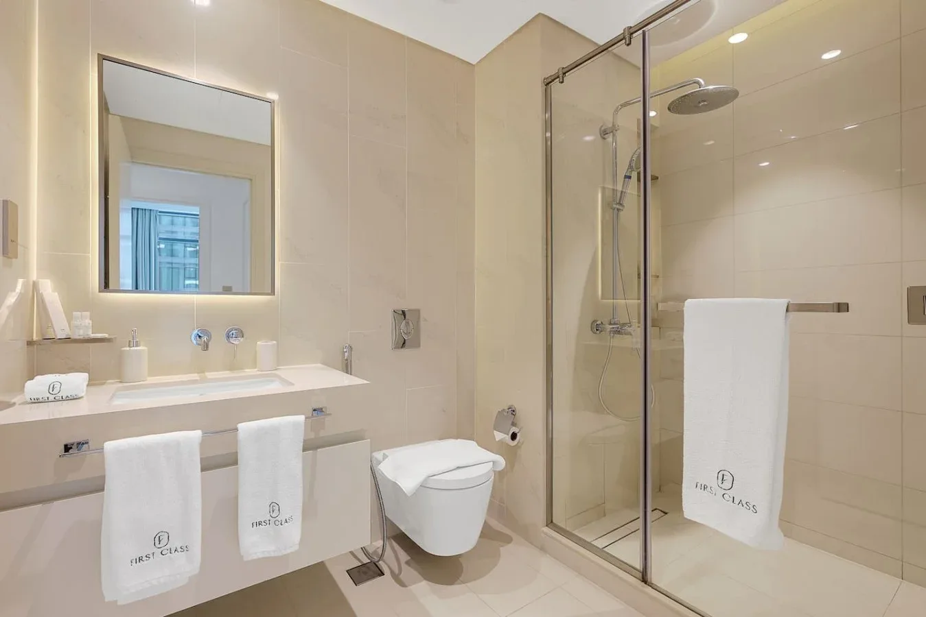 Un baño luminoso con lavabo, inodoro y ducha de vidrio.