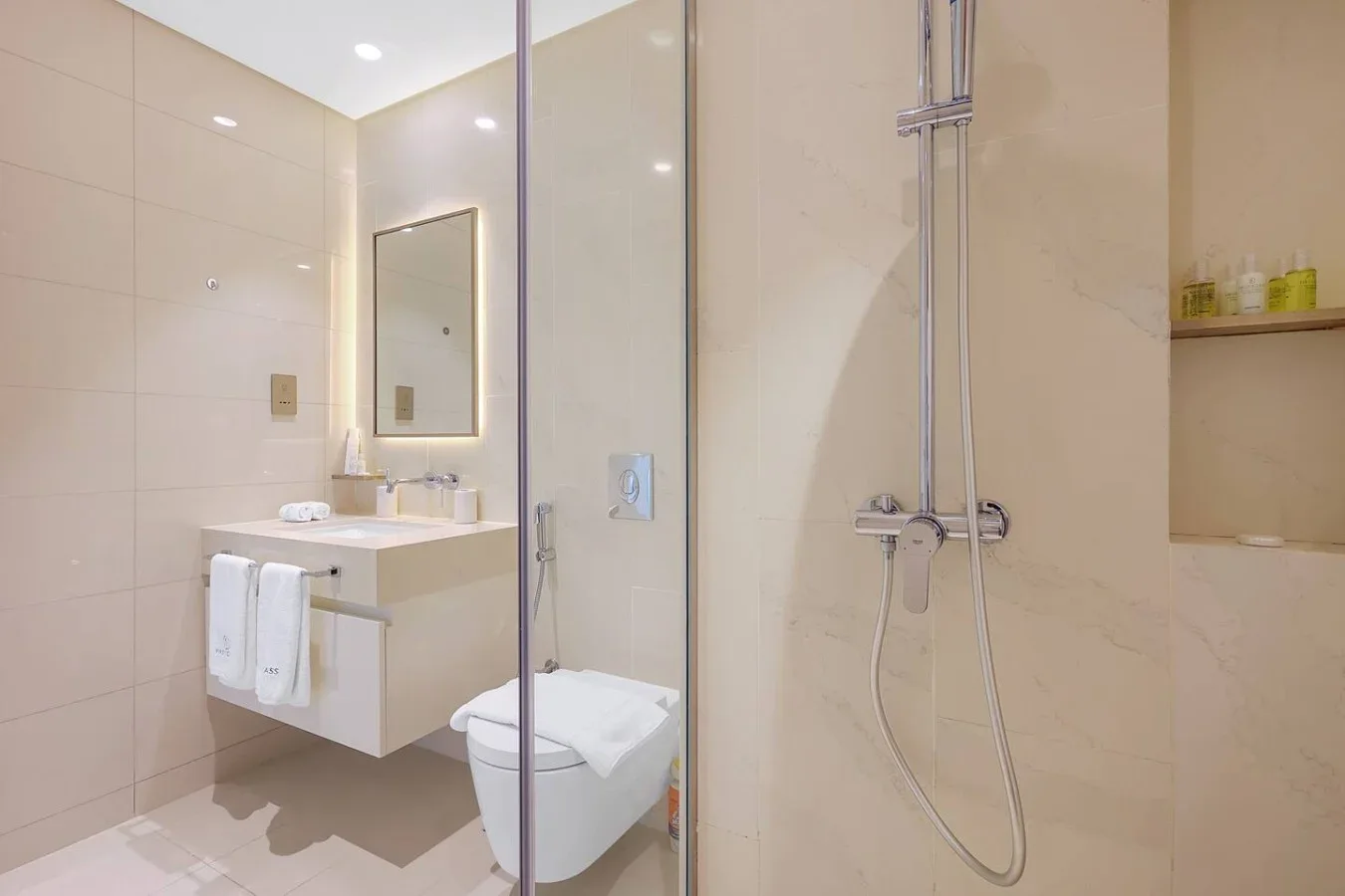 Un baño luminoso con ducha de vidrio y lavabo suspendido.