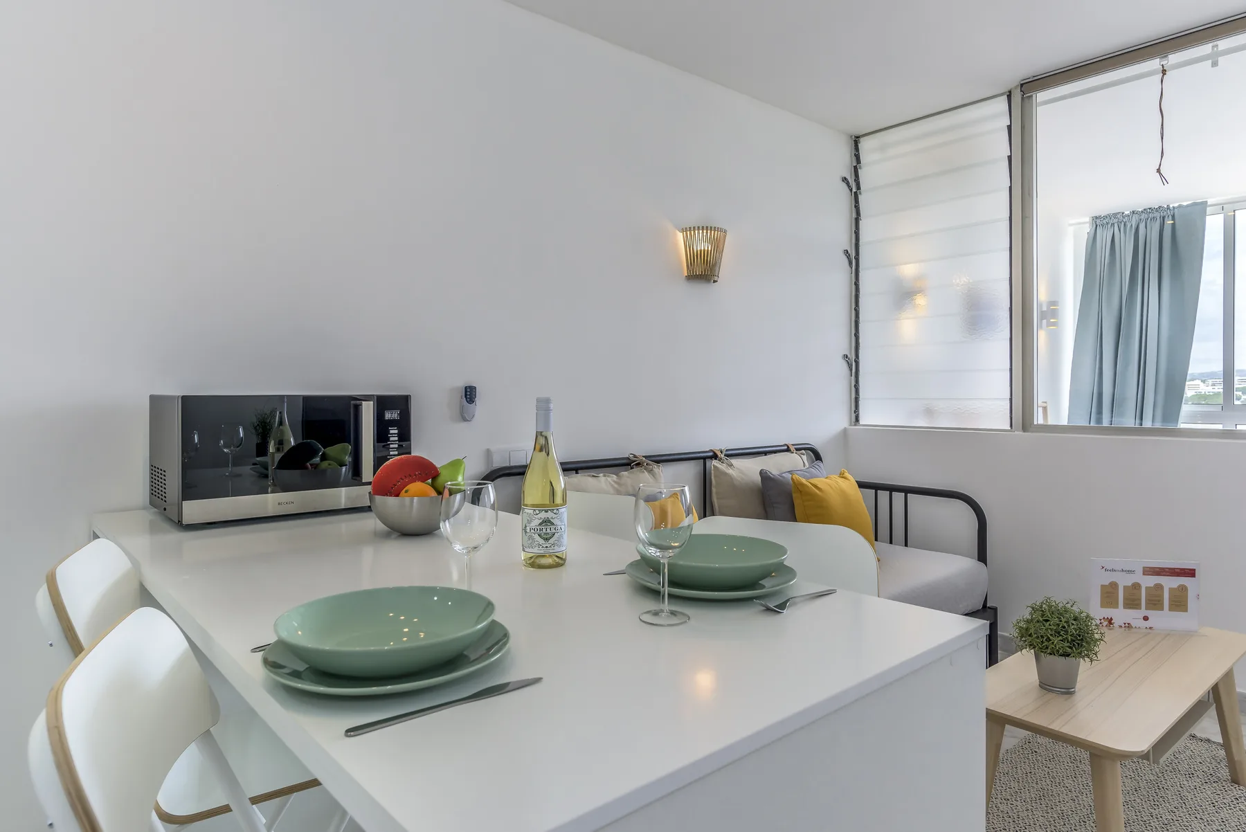 Comedor con la mesa puesta junto a una ventana y asientos.