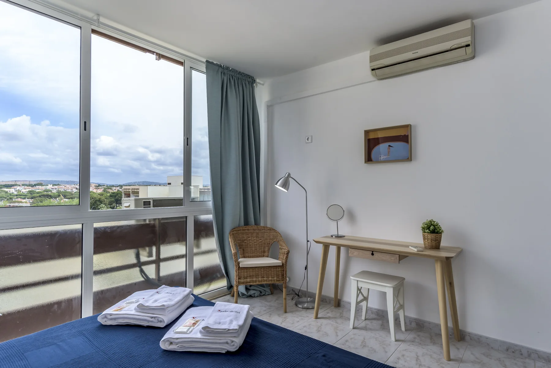 Una habitación luminosa con escritorio, silla y amplias ventanas con vistas al entorno.
