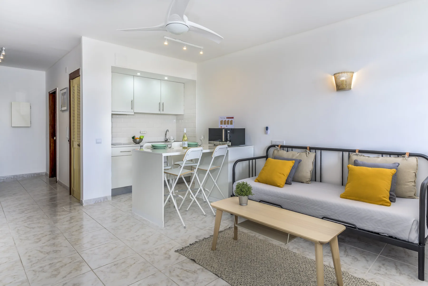 Una luminosa sala de estar abierta con asientos junto a una cocina compacta.
