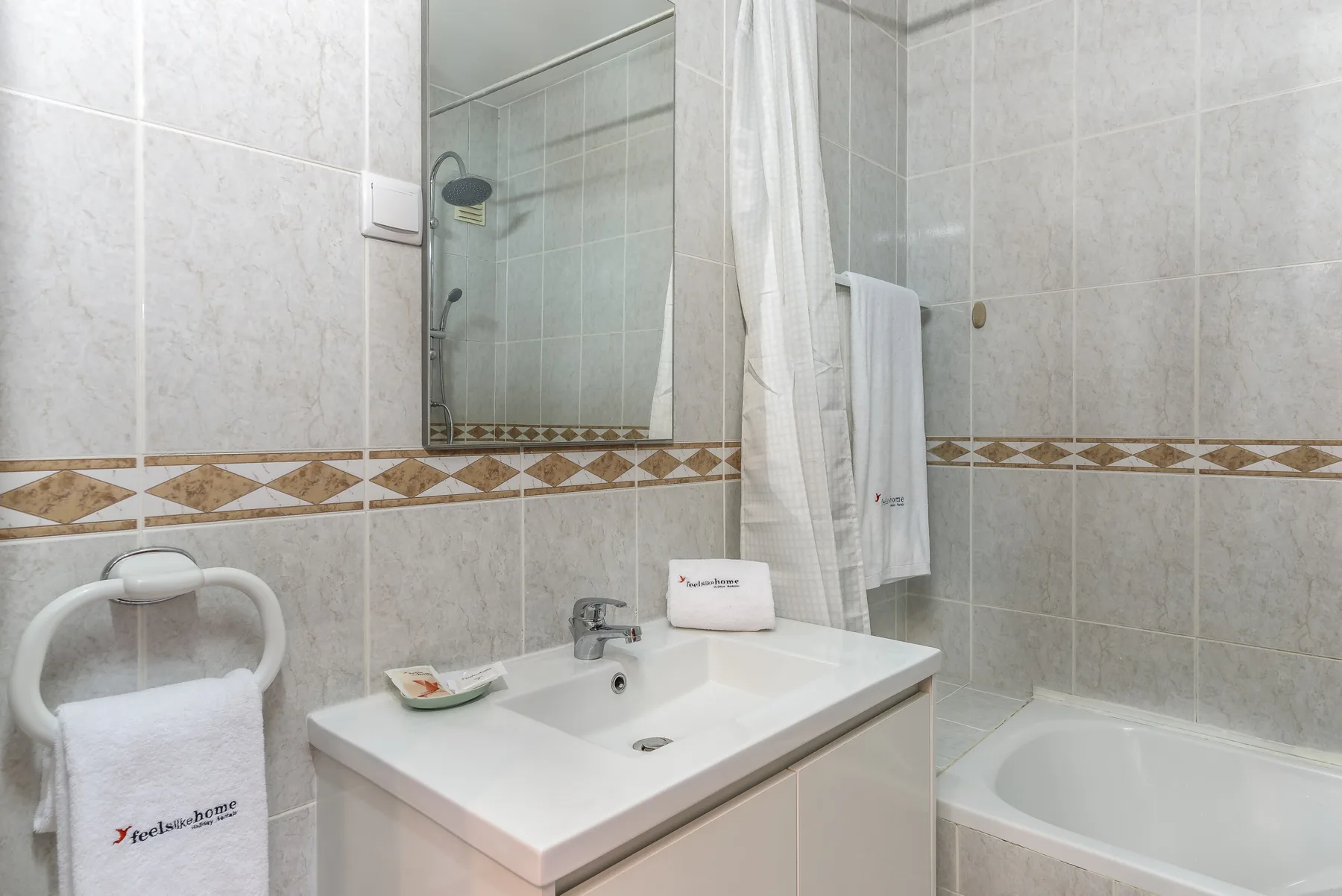 A bathroom with a sink, mirror, and bathtub.