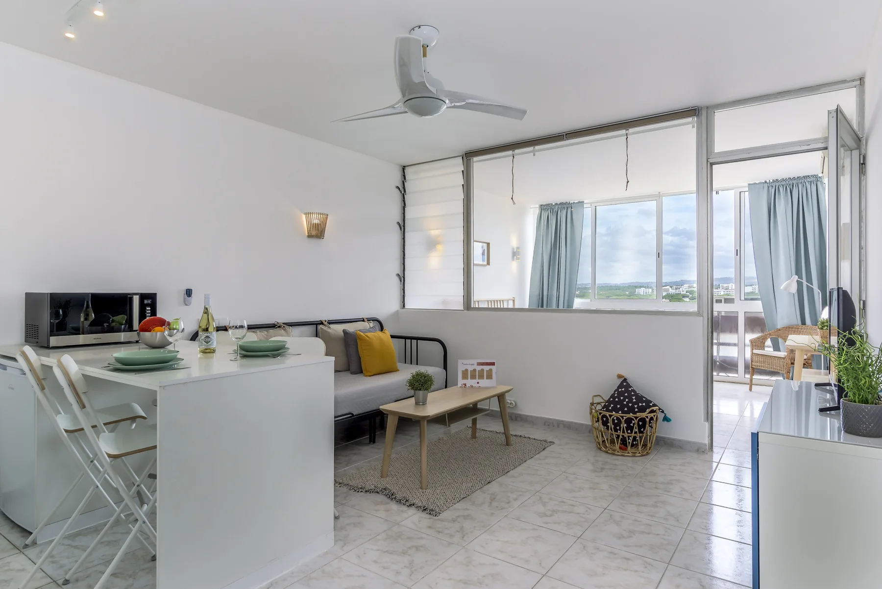 Una luminosa zona de estar y comedor con mesa, asientos y ventanas.