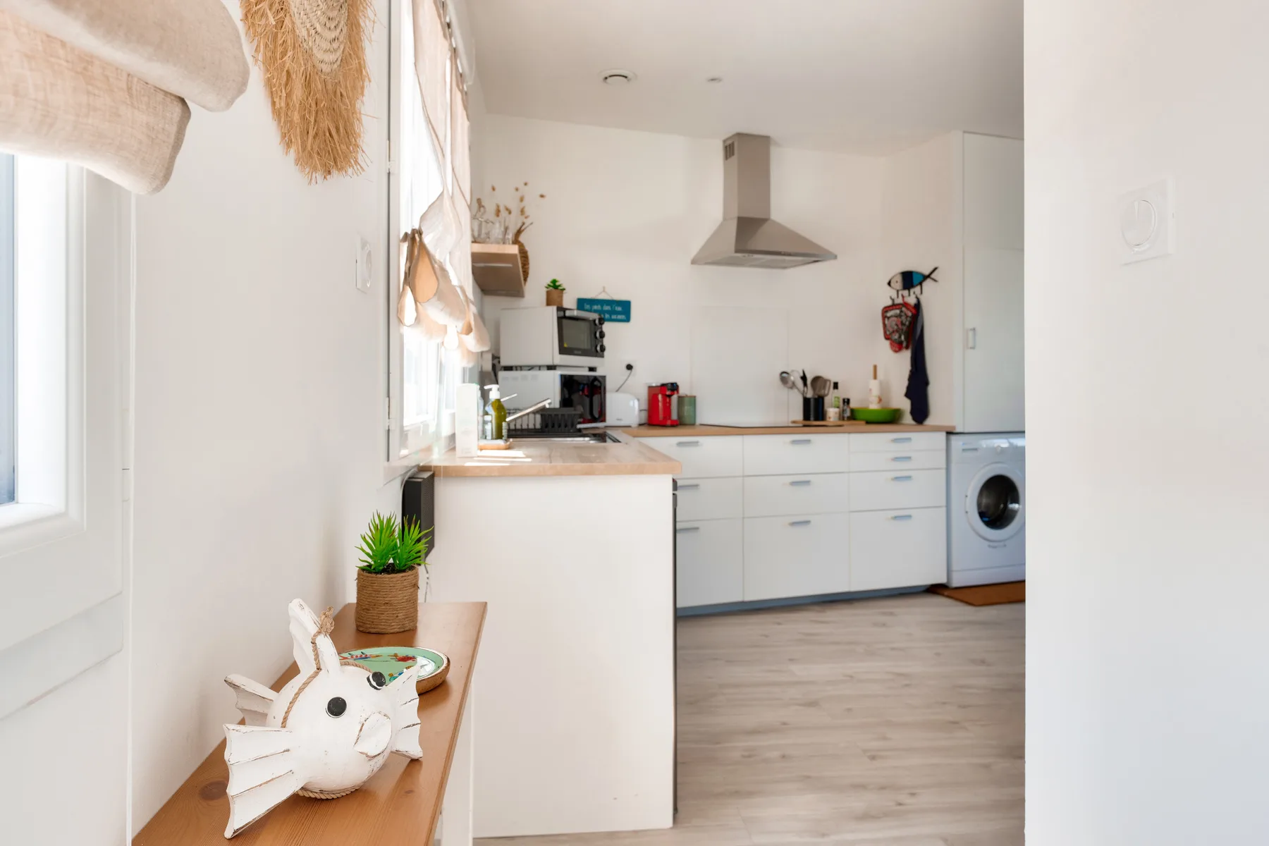 A compact kitchen with white cabinets and a counter sits beyond a bright entryway.