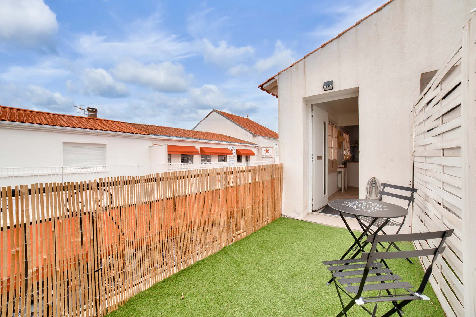 A small patio with outdoor seating beside an open doorway.