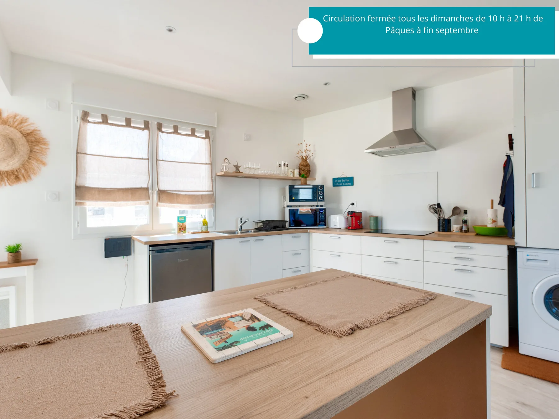 A bright kitchen with white cabinets and a large wooden countertop.