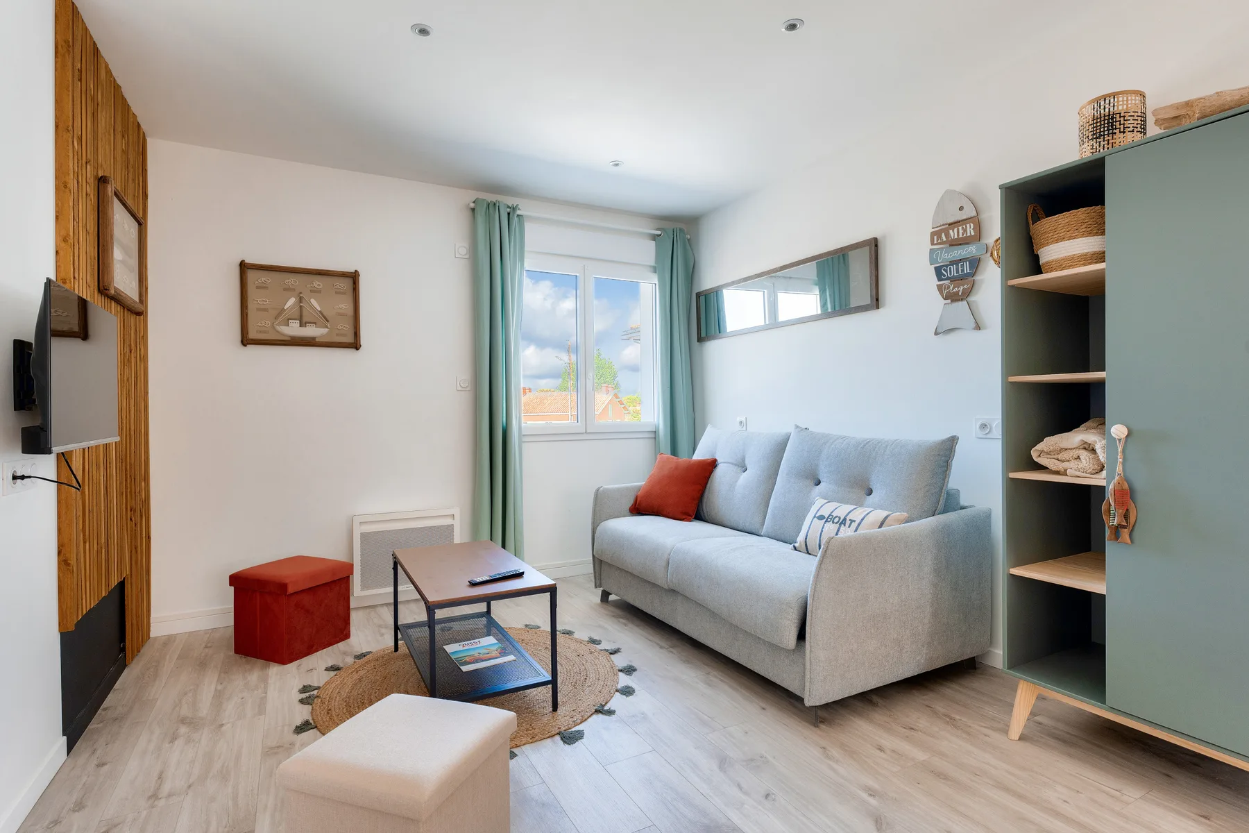 A living room with a sofa, coffee table, and window framed by pale curtains.