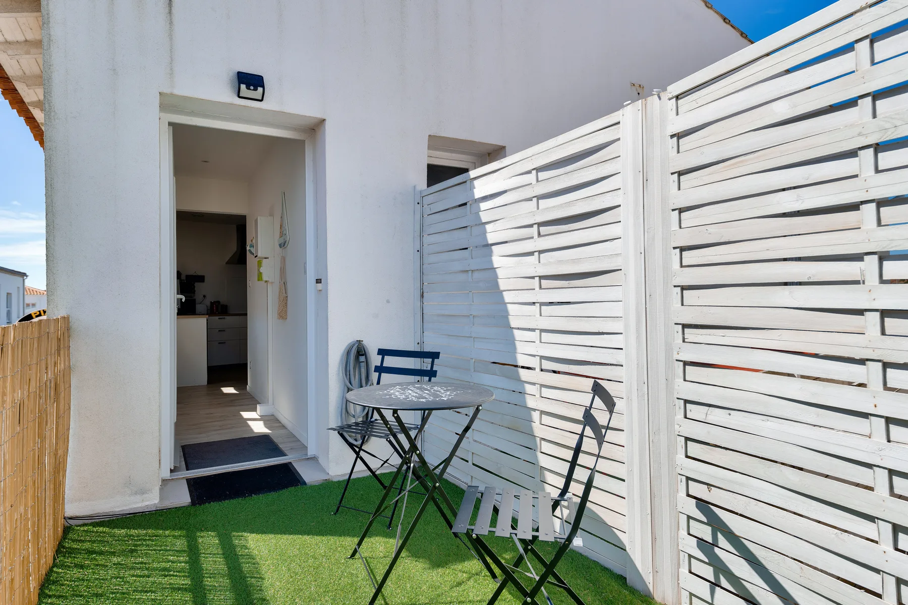 A small outdoor patio with seating beside an open doorway.