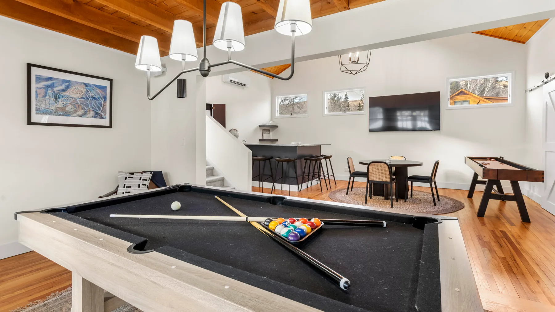 A game room with a pool table, seating, and a foosball table.