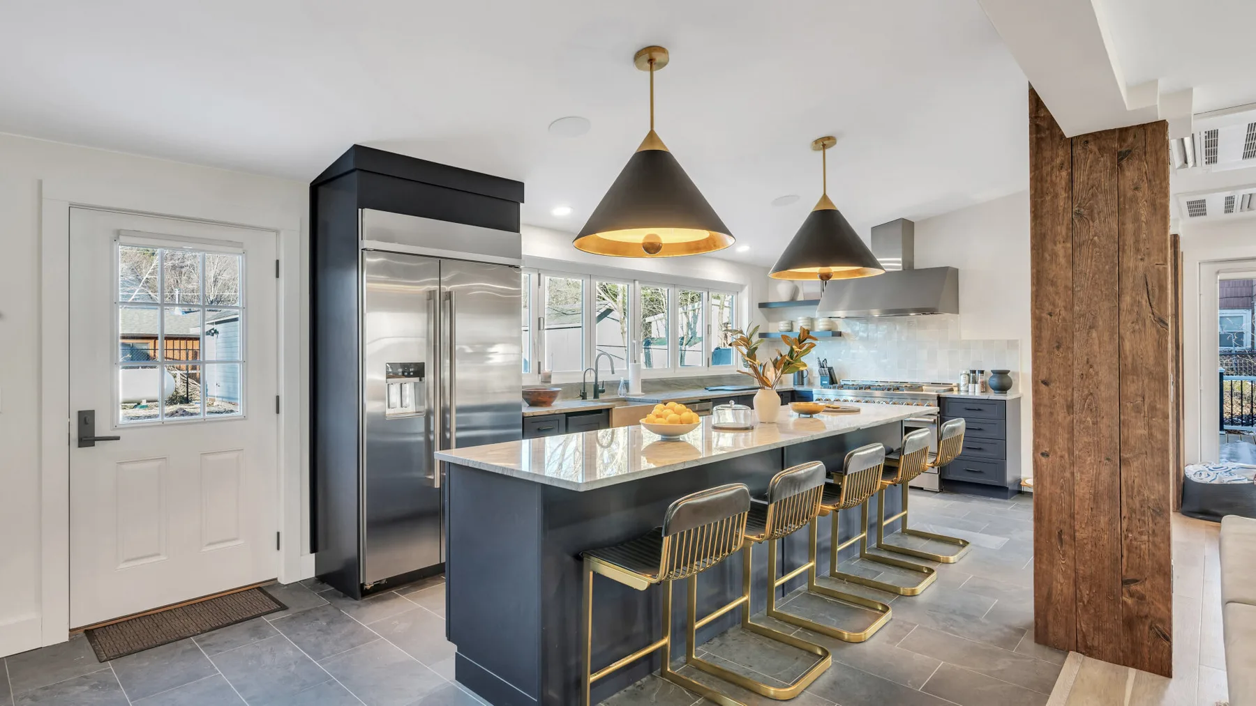 A modern kitchen with a central island, bar seating, and pendant lights.