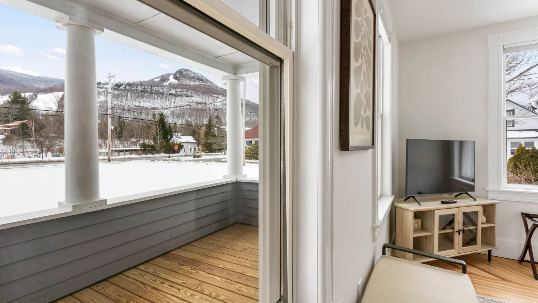 A bright living room opens onto a covered porch with a mountain view.