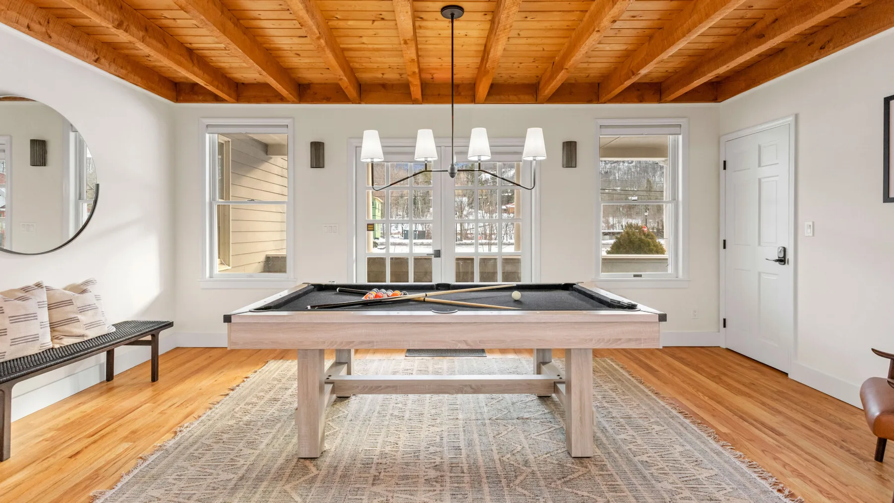 A game room with a pool table beneath a wooden ceiling.