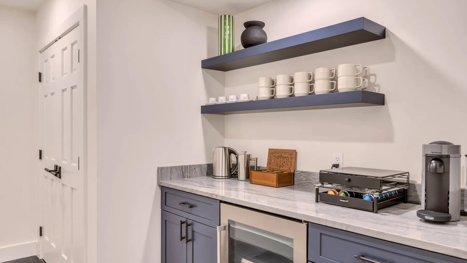 A compact kitchenette with a countertop, shelves, and small appliances.