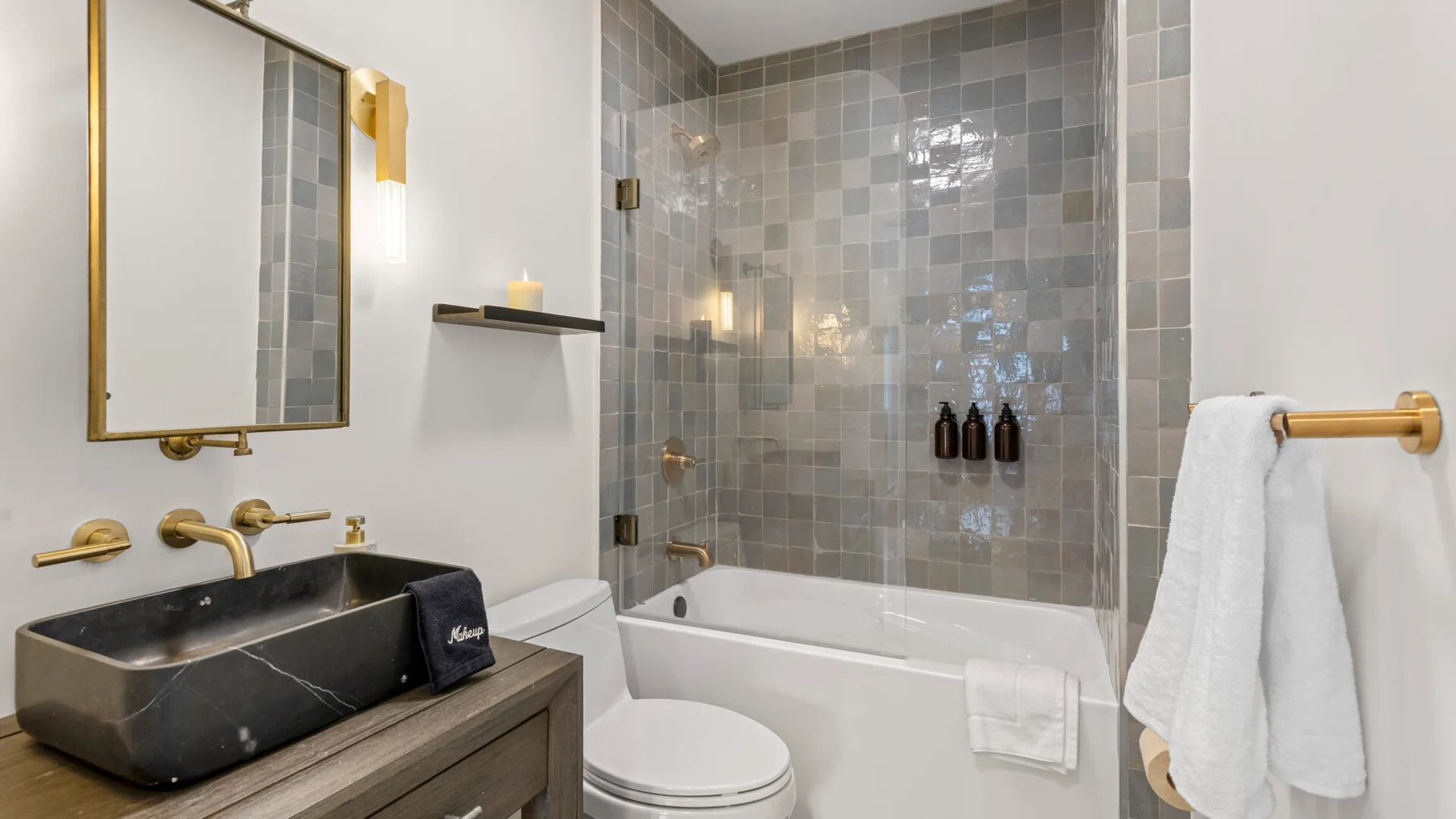 A bathroom with a dark sink, toilet, and tiled shower area.