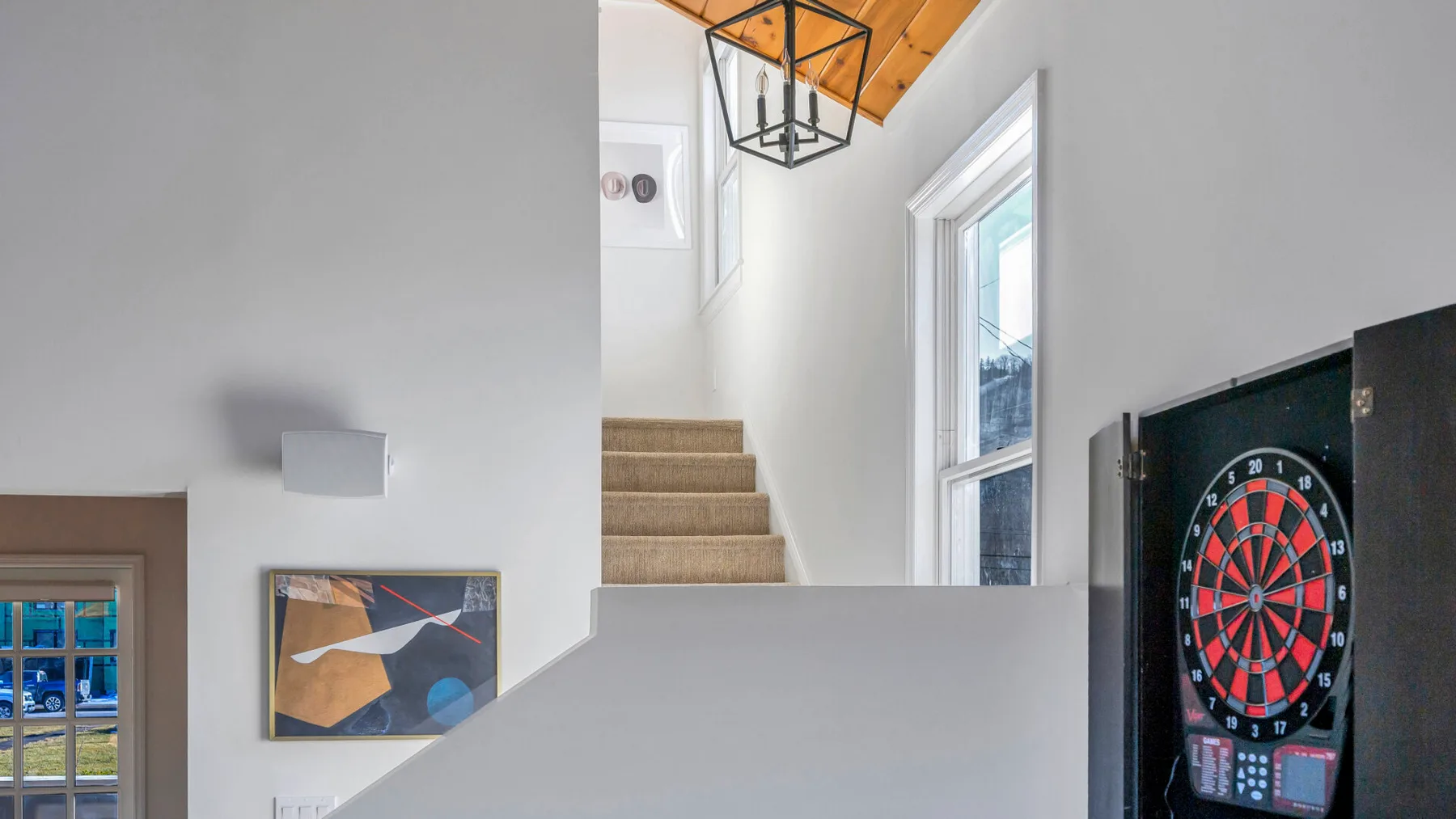 An indoor stairway with a dartboard mounted on the wall nearby.