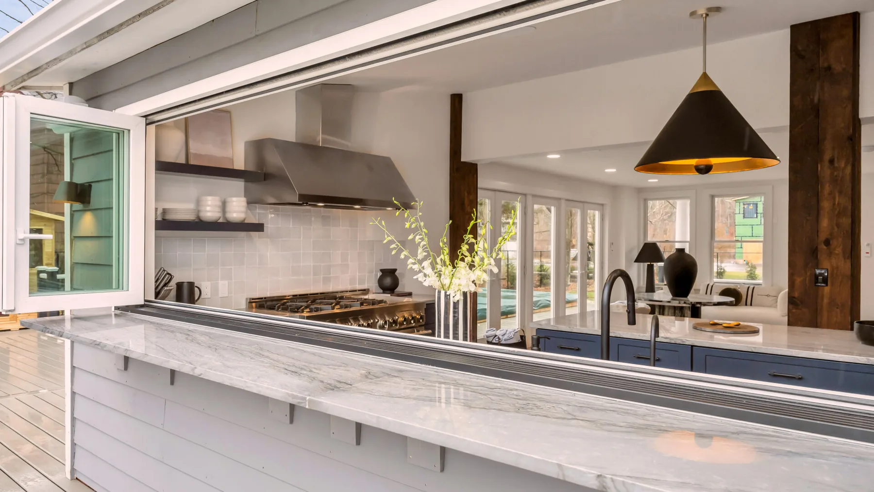 A bright kitchen with a long island, cooktop, and windows overlooking the patio.