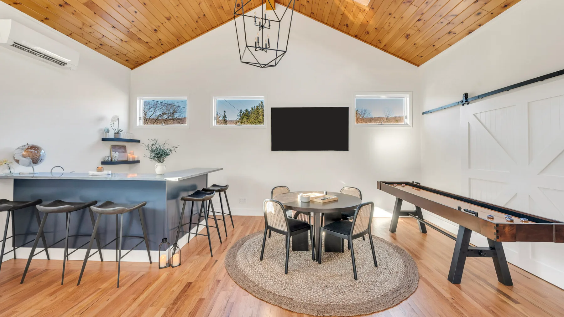 A bright open dining and recreation room with a table, counter seating, and pool table.