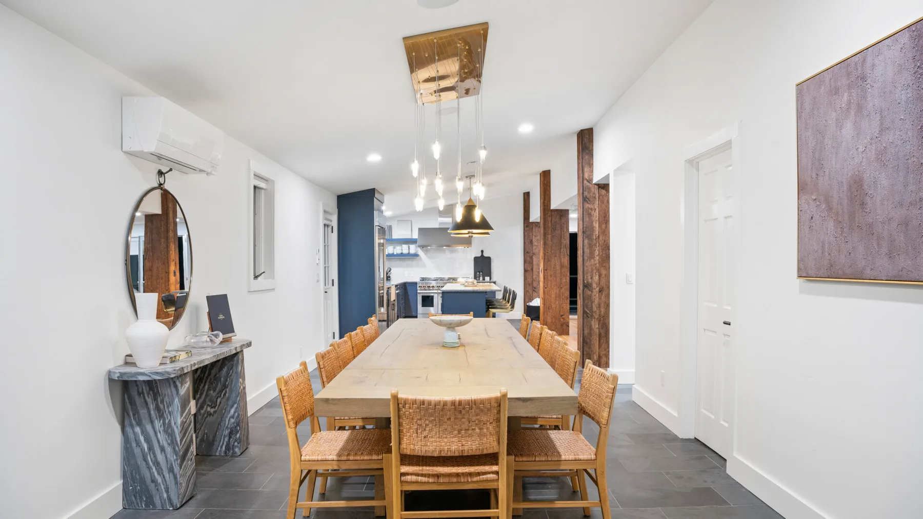 A dining area with a long wooden table and chairs beside the kitchen.