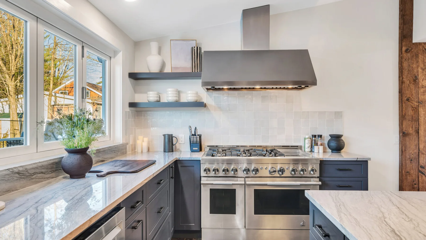 A bright kitchen with a stainless-steel range beneath a wide hood.