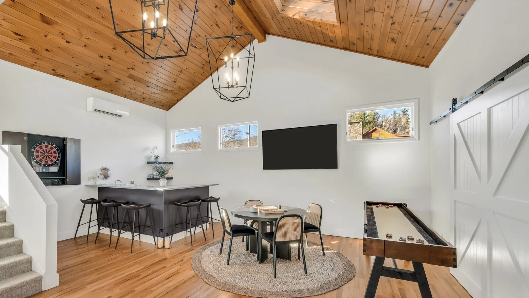A bright open-plan room with a dining table, bar seating, and a foosball table.
