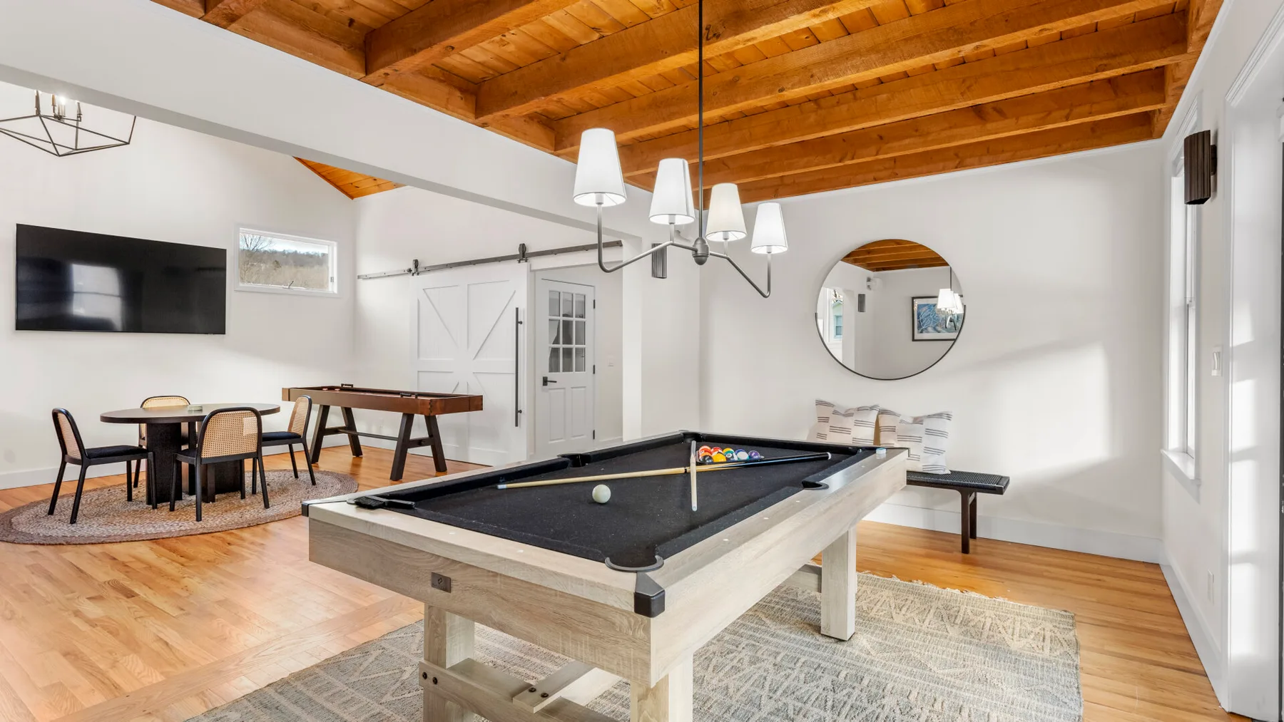 A recreation room with a pool table, dining table, and television.