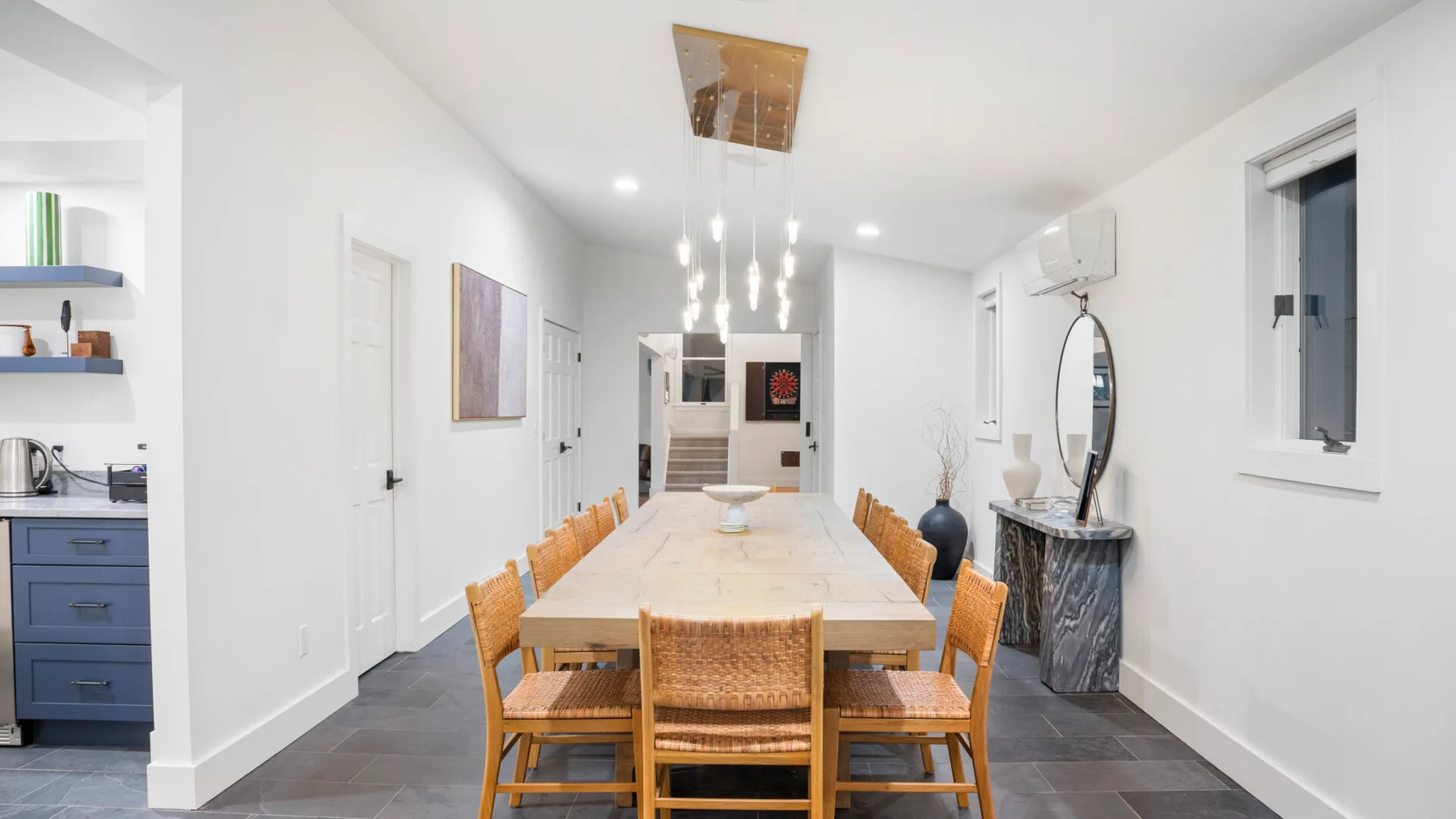 A bright dining room with a long table and wooden seating.