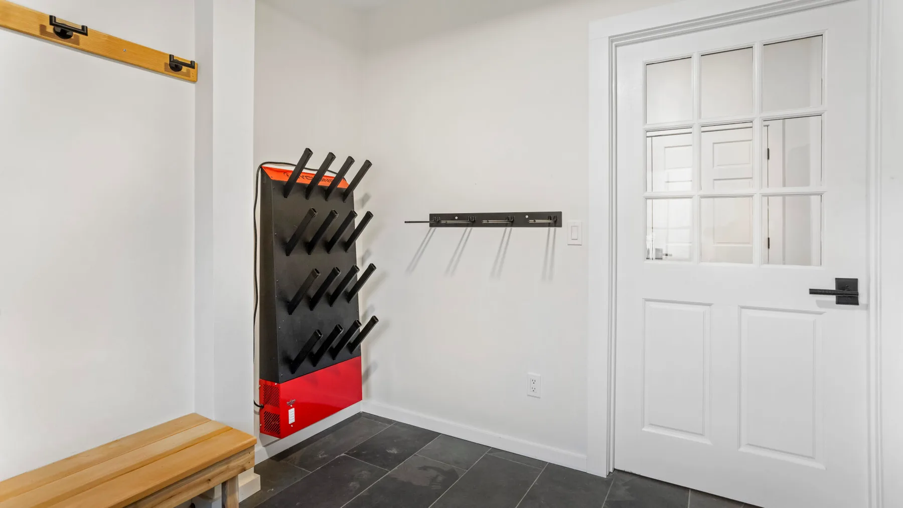 A bright entryway has a white paneled door and a wall-mounted shoe rack.