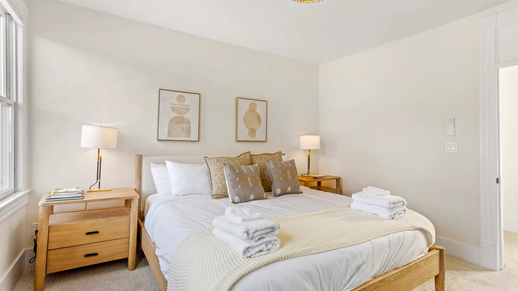 A bright bedroom with a neatly made bed and folded towels.