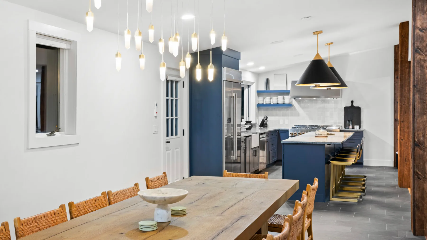 A bright dining area with a wooden table beside a kitchen island.