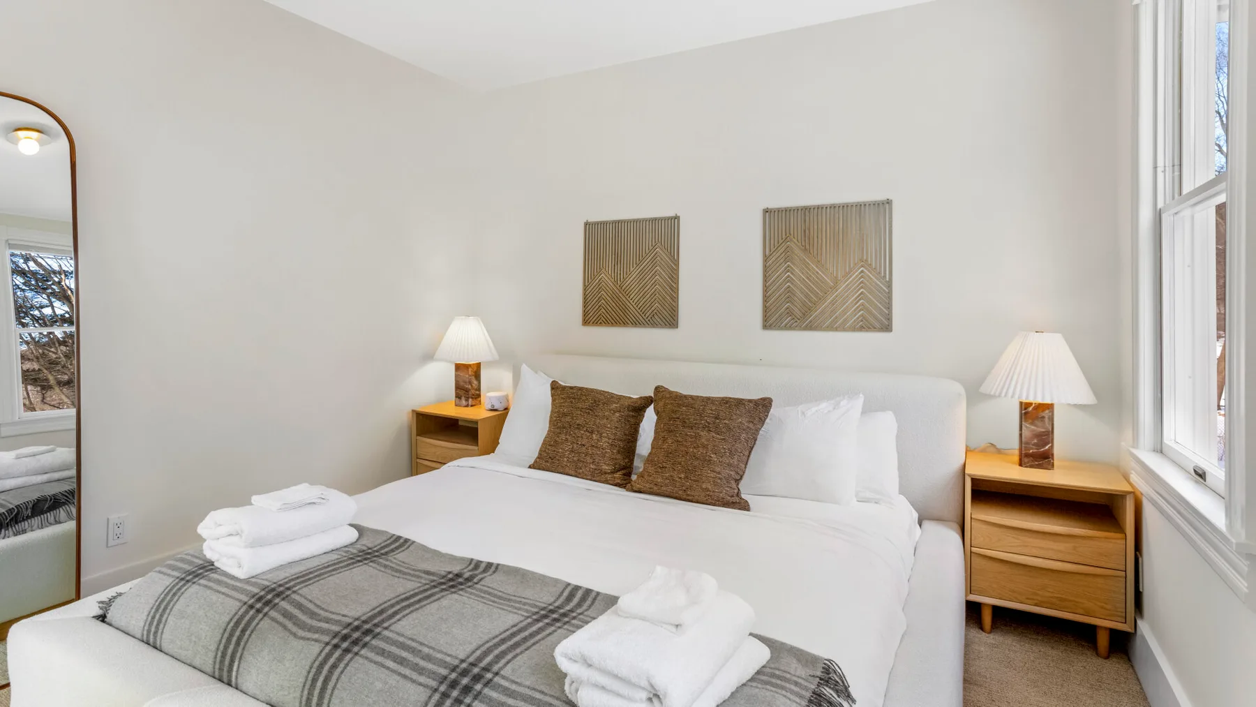 A bright bedroom with a neatly made bed and matching bedside tables.