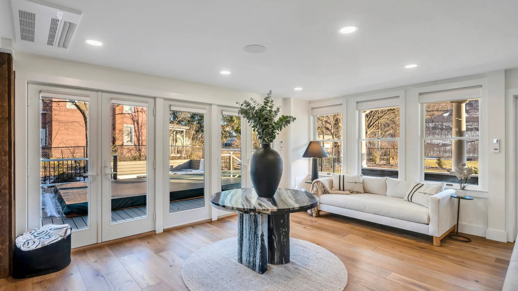 A bright living room with a round table and seating beside large windows.