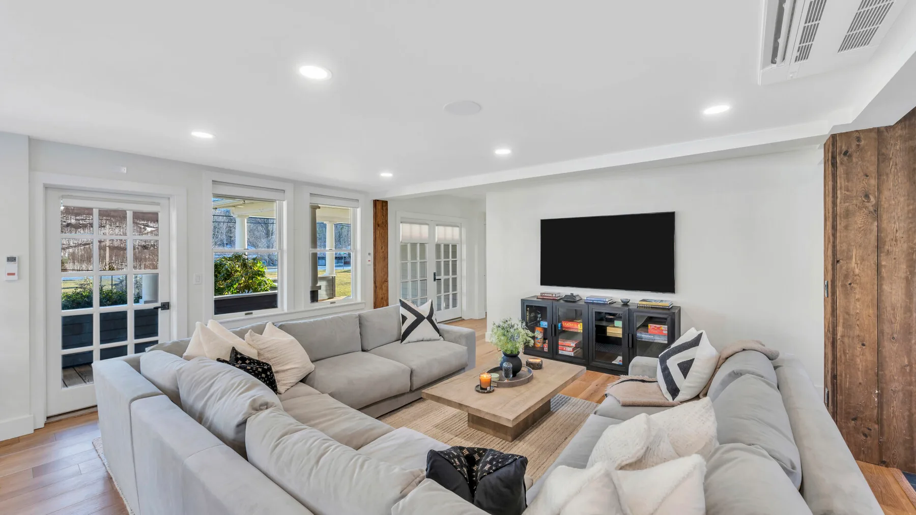 A bright living room with sectional seating, a coffee table, and a television.