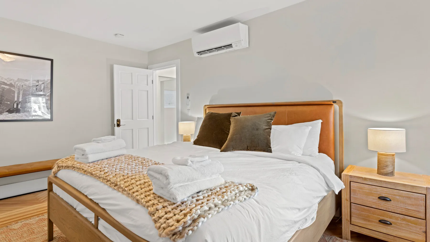 A bedroom with a neatly made bed and folded towels.