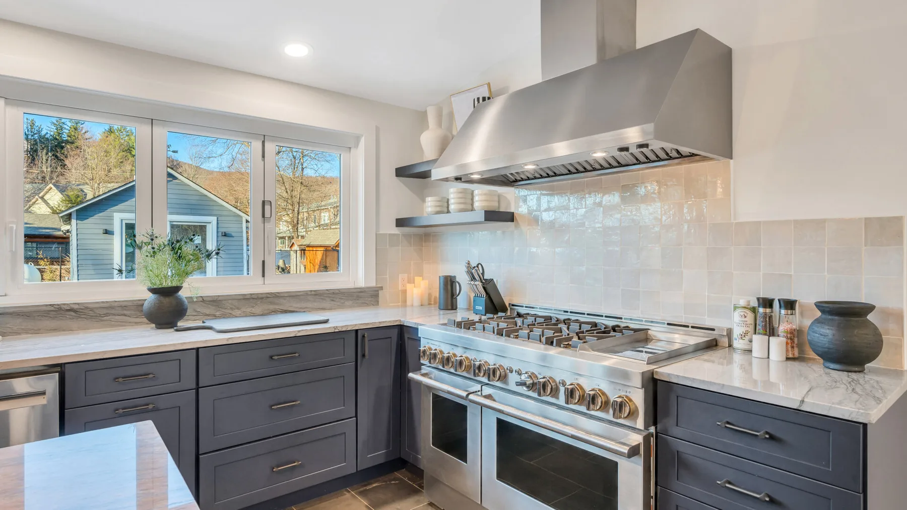 A bright kitchen with dark cabinetry, a large range, and broad windows.