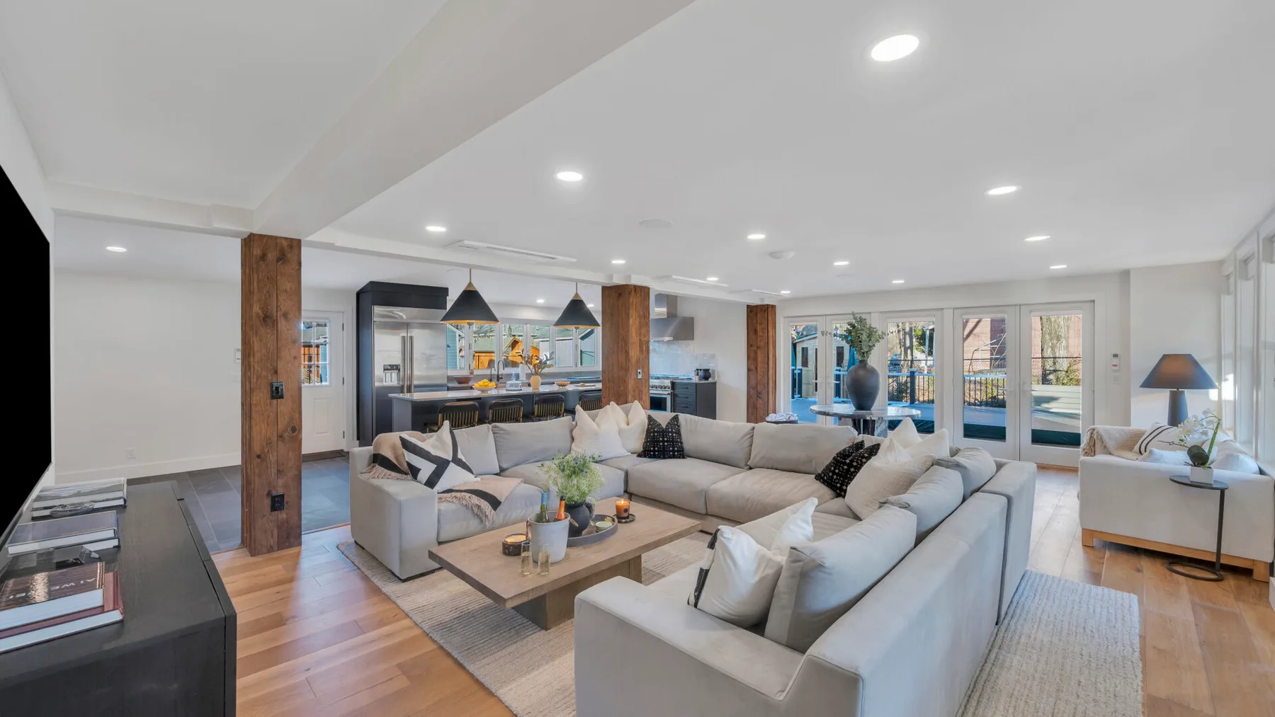 A bright living room with sectional seating, a coffee table, and large windows.