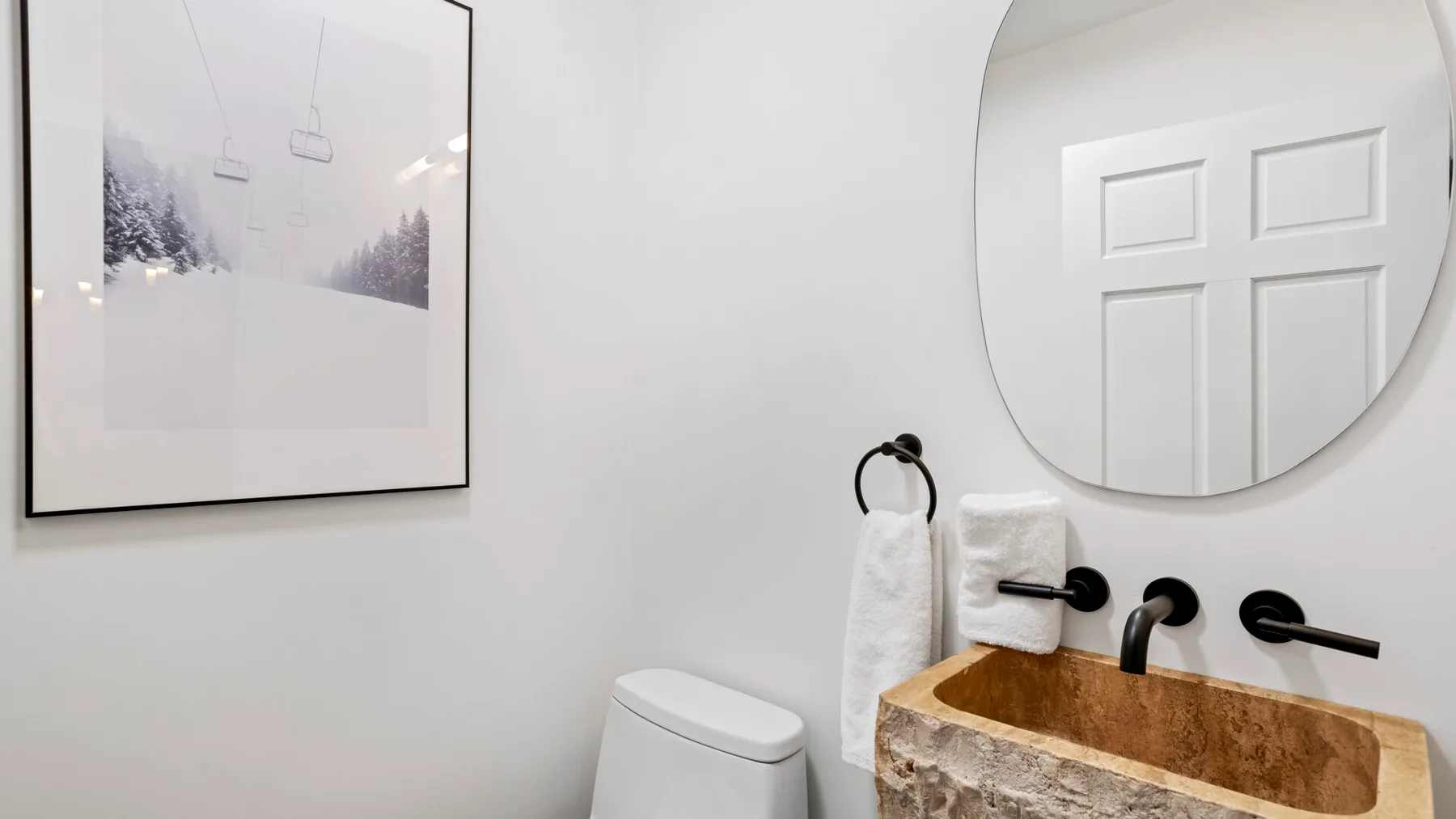 A bathroom vanity with a basin, wall mirror, and framed picture.