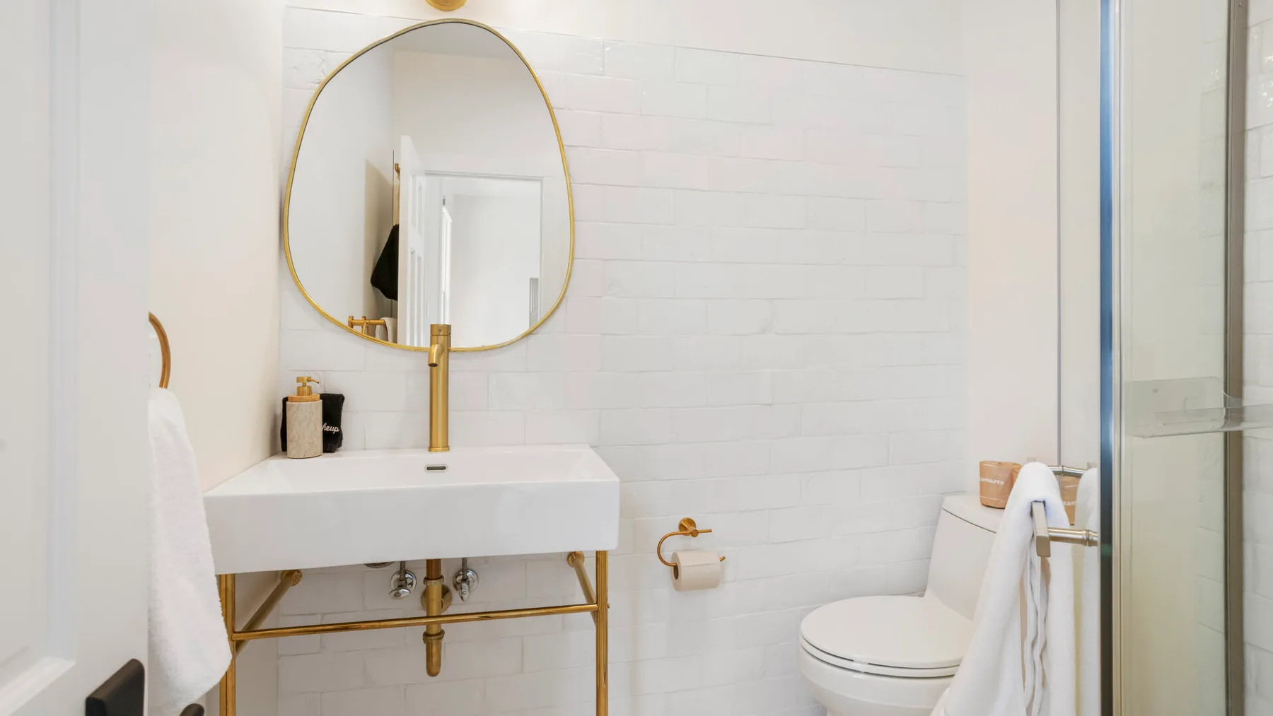 A bright bathroom with a sink, toilet, and glass shower enclosure.
