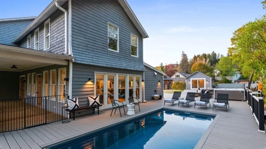 A blue-sided house opens onto a pool deck with outdoor seating.
