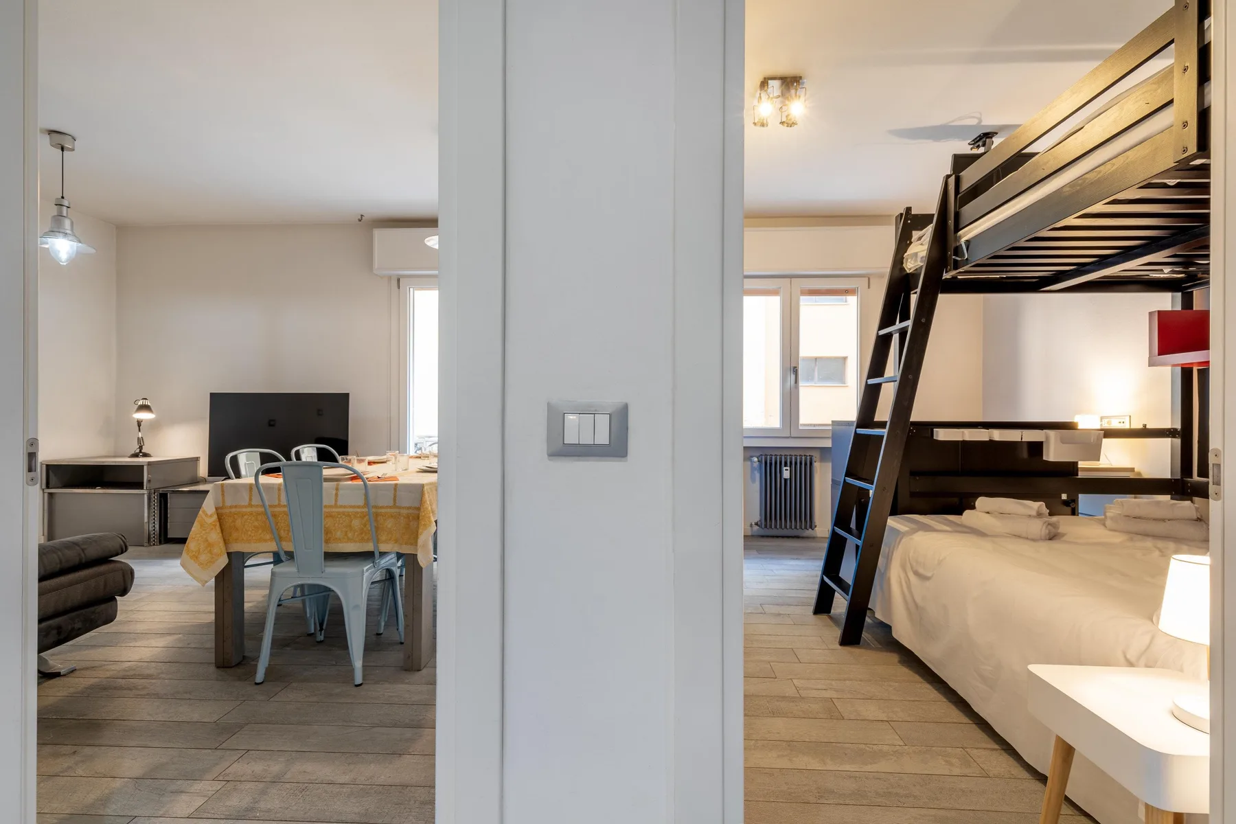 Un dormitorio con una litera junto a una zona de comedor con mesa y sillas.