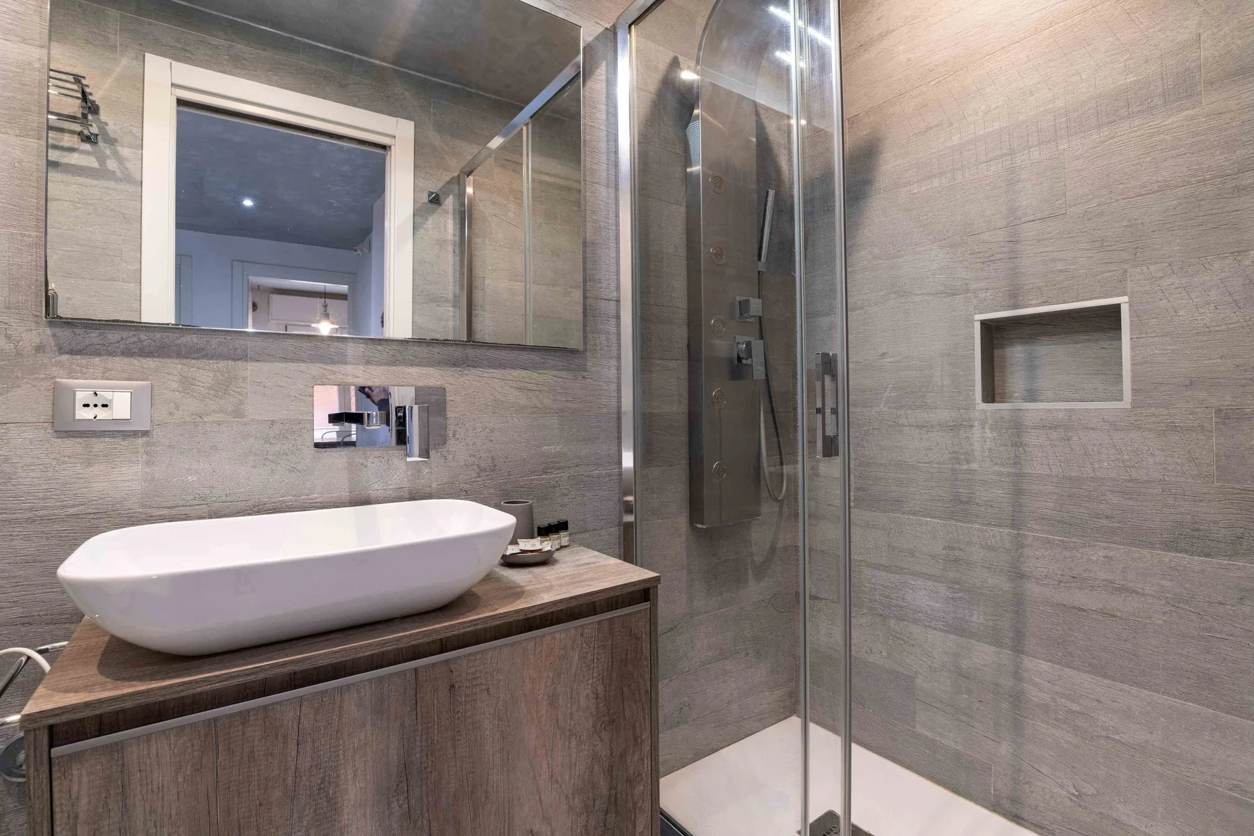 Un baño moderno con lavabo sobre encimera y ducha de vidrio.