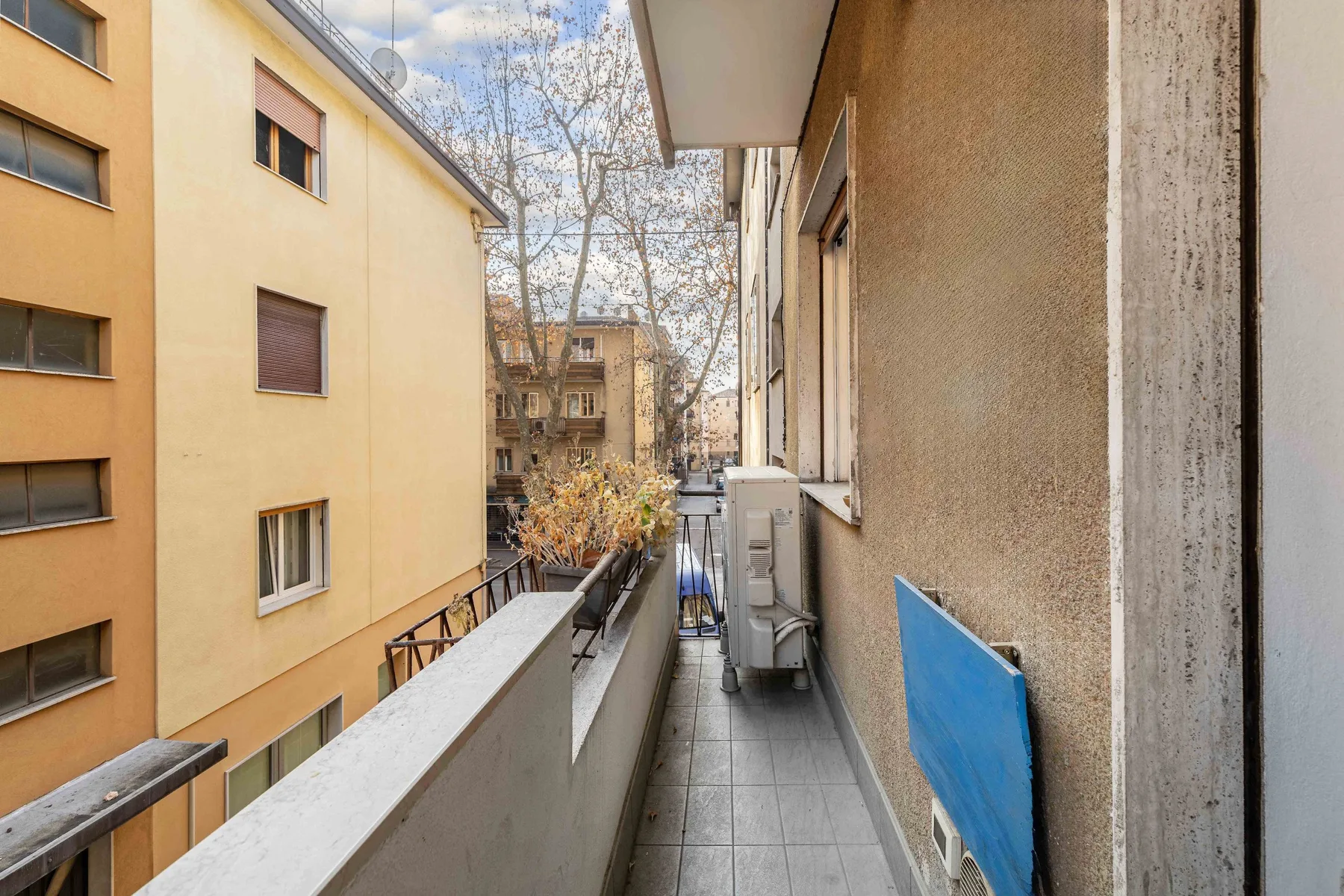 Un pasillo estrecho de balcón da a edificios de apartamentos vecinos.